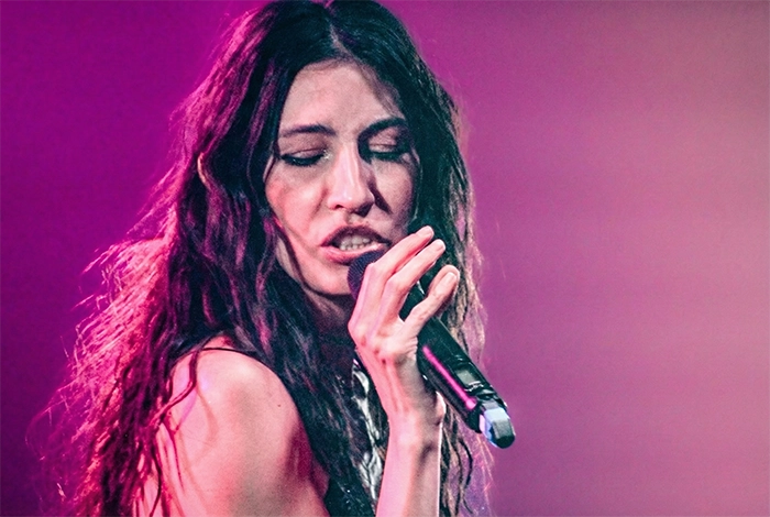 Cantante en primer plano interpretando en un escenario iluminado en tonos púrpura Daniela Spalla y Esteman en Madrid