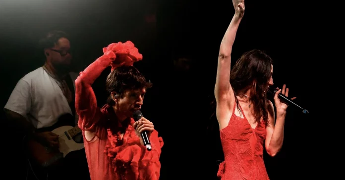 Dos artistas cantando en directo con vestuario rojo durante un concierto