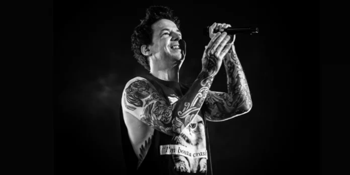 Vocalista de Simple Plan sonriendo con el micrófono en una fotografía en blanco y negro de su concierto en Madrid